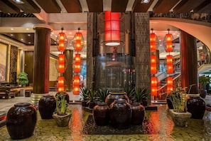 Un hall d’entrée agrémenté d’une fontaine centrale, de plusieurs luminaires de style lanterne et de plantes en pot.