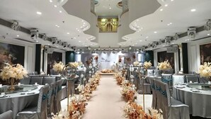 A banquet hall with round tables, floral centerpieces, and a central aisle. - Hengsheng Kejia Courtyard (Xinfeng)