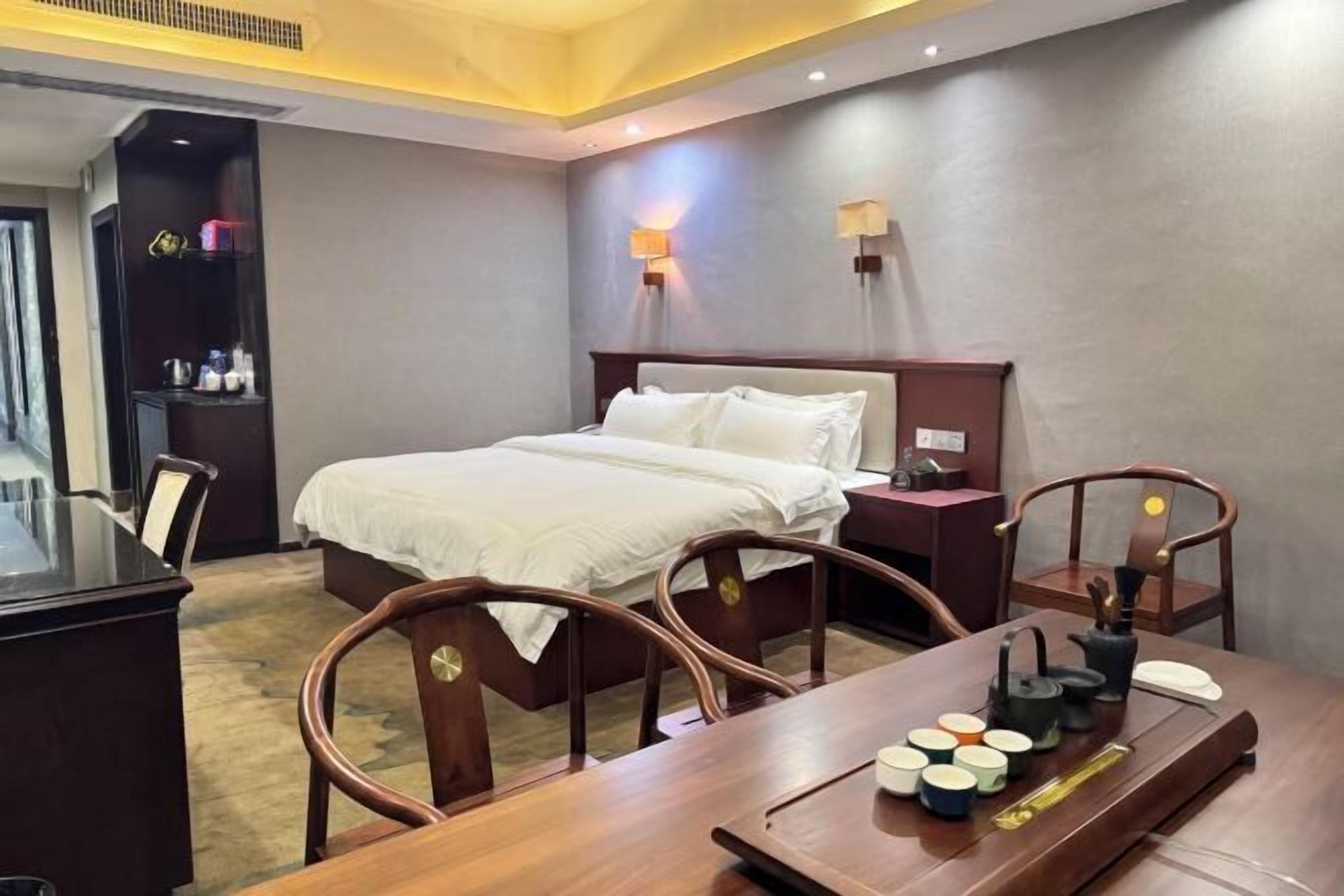 Een hotelkamer met een bed, nachtkastjes, een bureau en stoelen.