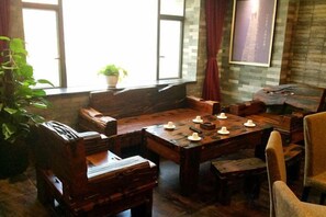 Una mesa de comedor de madera tradicional con sillas, una planta en maceta y una ventana con cortinas.