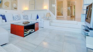 A modern living room with a white sofa, a red coffee table, and a flat-screen TV. There is a staircase leading to another level. - Villa Bonanova Style (Palma)