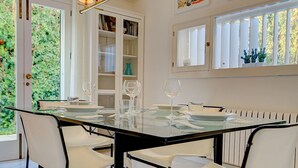 A dining area with a glass table, white chairs, and a bookshelf in the background. - Villa Bonanova Style (Palma)