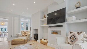 En moderne stue med en sofa, et træbord og et fjernsyn ophængt på væggen.