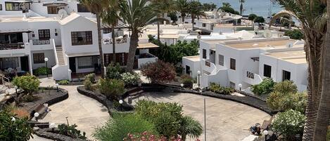 A coastal residential area with white buildings, palm trees, and a clear view of the sea.