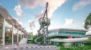 A modern building with a unique spiral staircase structure in the center, surrounded by a plaza with spherical seating and a large glass facade. - Hollywood Large Studio Close to Beach & Casino LB3 (Hollywood)