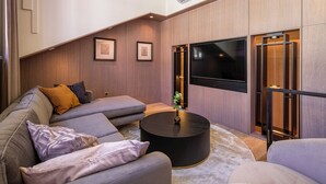 Een moderne woonkamer met een hoekbank, een ronde salontafel en een grote flatscreen televisie.