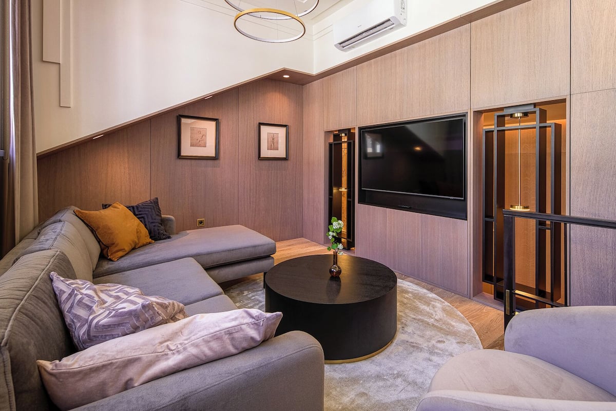 Ein modernes Wohnzimmer mit einer Eckcouch, einem runden Couchtisch und einem großen Flachbildfernseher.