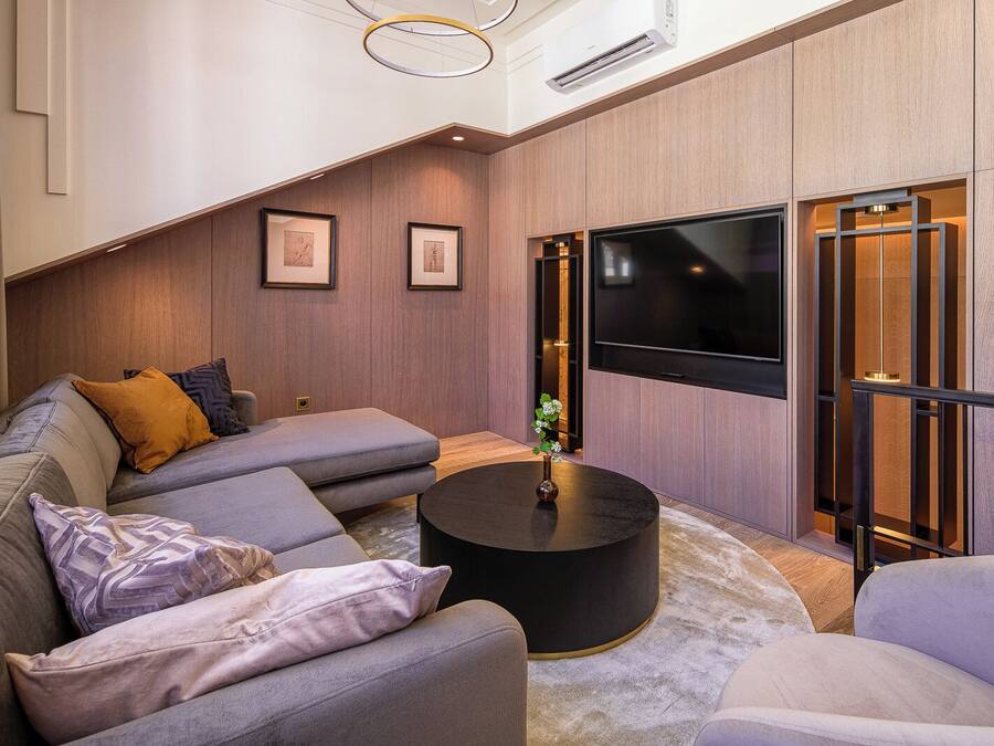 A modern living room with a sectional sofa, a round coffee table, and a large flat-screen TV.