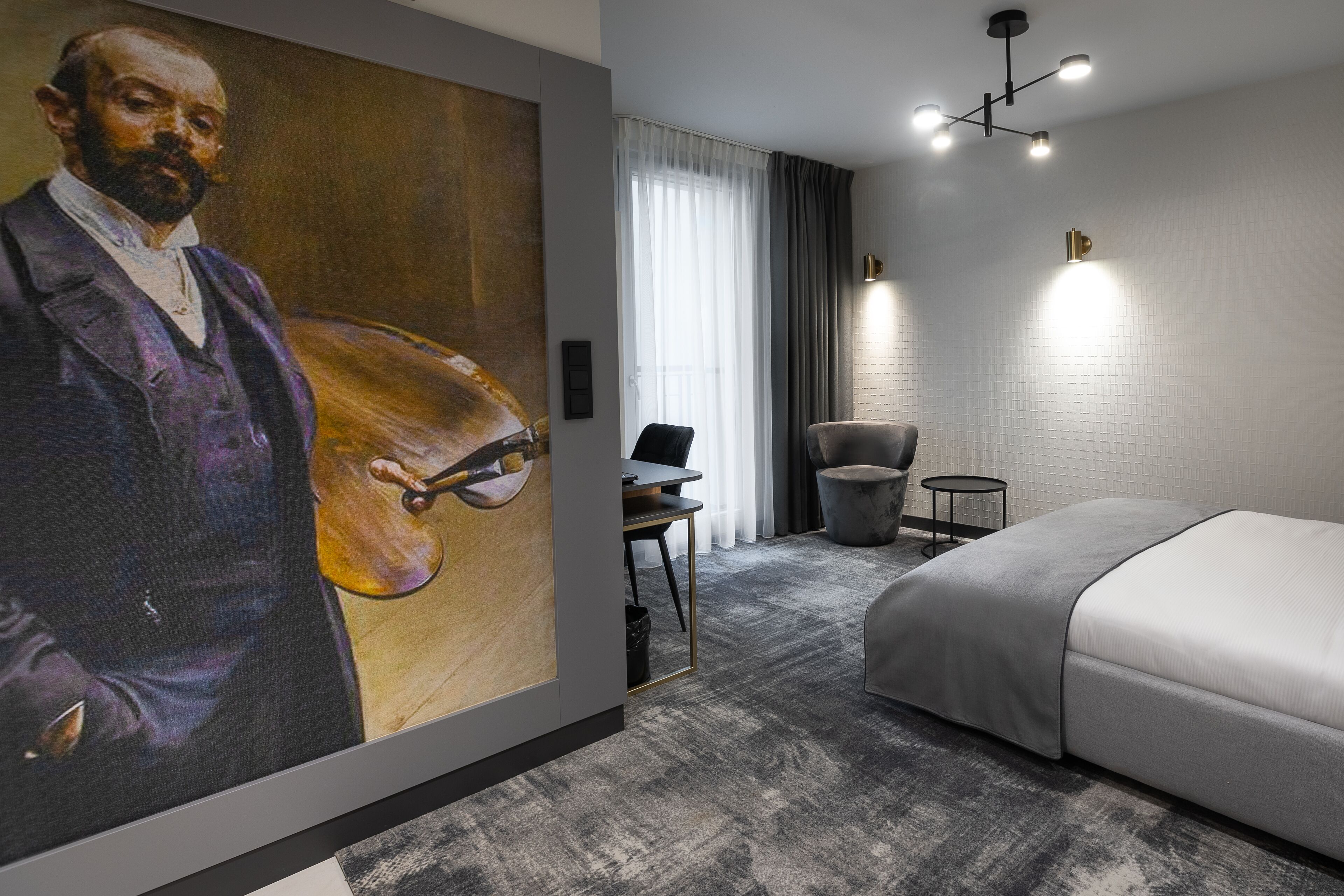 Une chambre d’hôtel moderne avec un grand tableau, un lit, un bureau et une chaise.