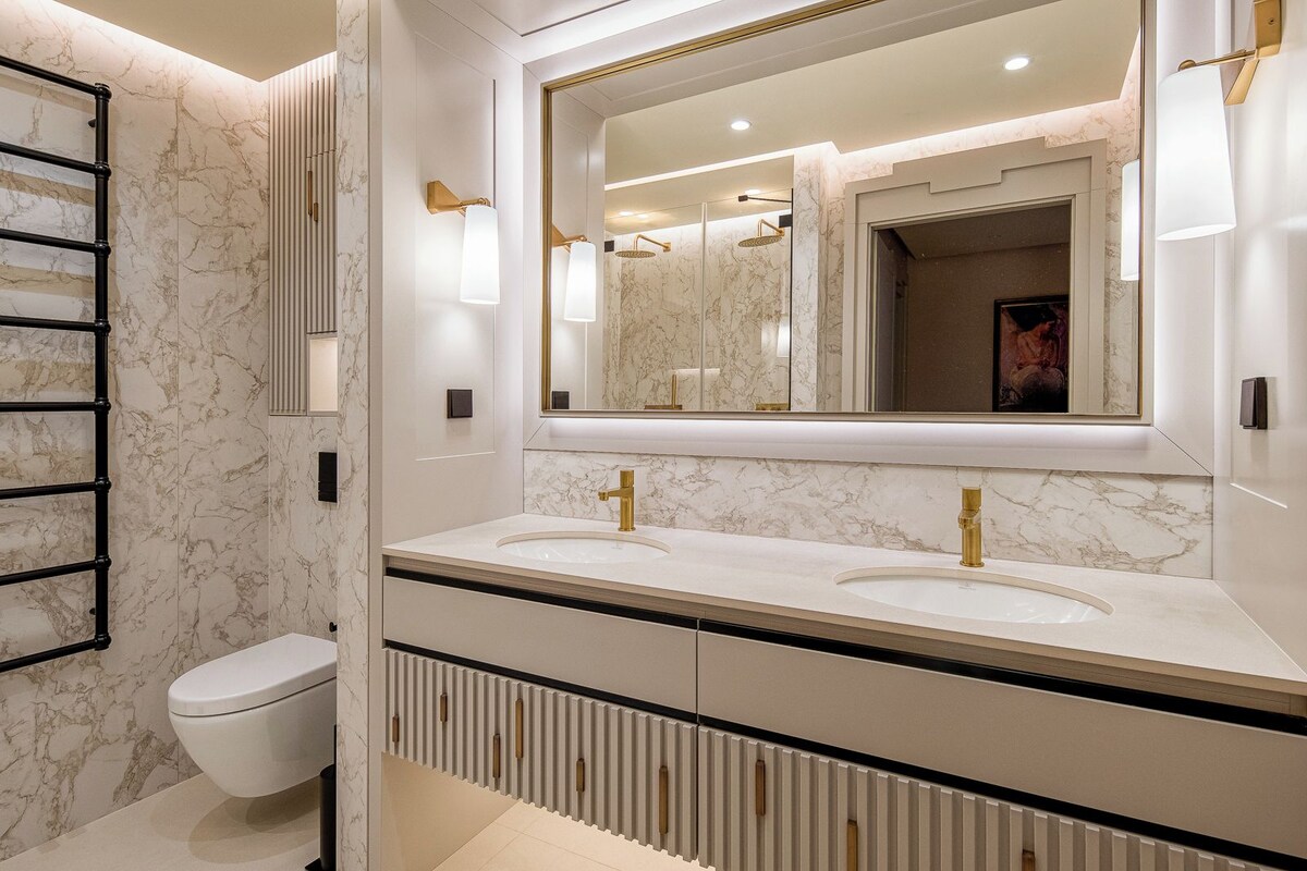 Une salle de bain moderne avec deux lavabos, des toilettes et un grand miroir.