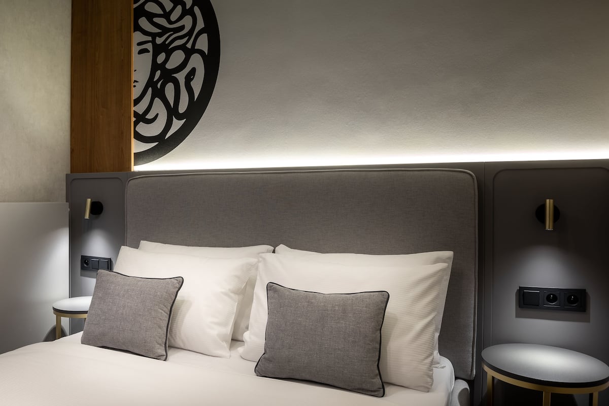 Ein modernes Hotelzimmer mit einem großen Bett, zwei Nachttischen und einer dekorativen Wandgestaltung.