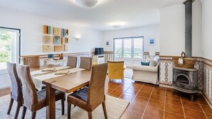 A spacious living area with a dining table, chairs, a sofa, a fireplace, and a television. - Casa da Leira (Vila Nova de Cerveira)