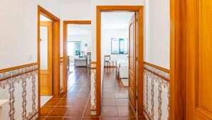 A hallway with tiled flooring, wooden doors, and a view into a living area with a sofa and a coffee table. - Casa da Leira (Vila Nova de Cerveira)