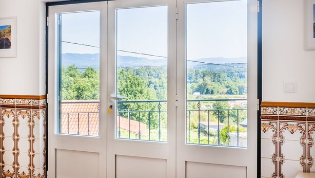 A room with a large window overlooking a green landscape and mountains. - Casa da Leira (Vila Nova de Cerveira)