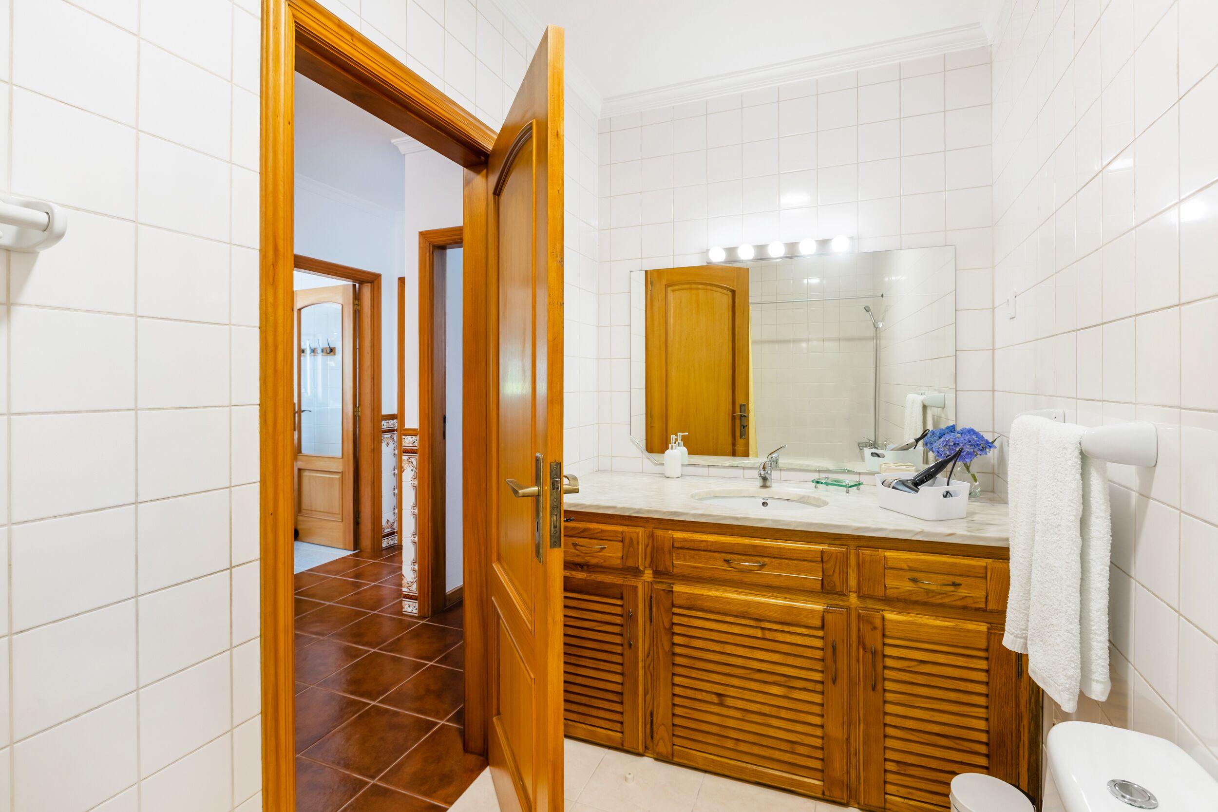 A modern bathroom with a wooden vanity, a large mirror, and a white toilet.