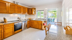 A modern kitchen with wooden cabinets, granite countertops, and stainless steel appliances. - Casa da Leira (Vila Nova de Cerveira)