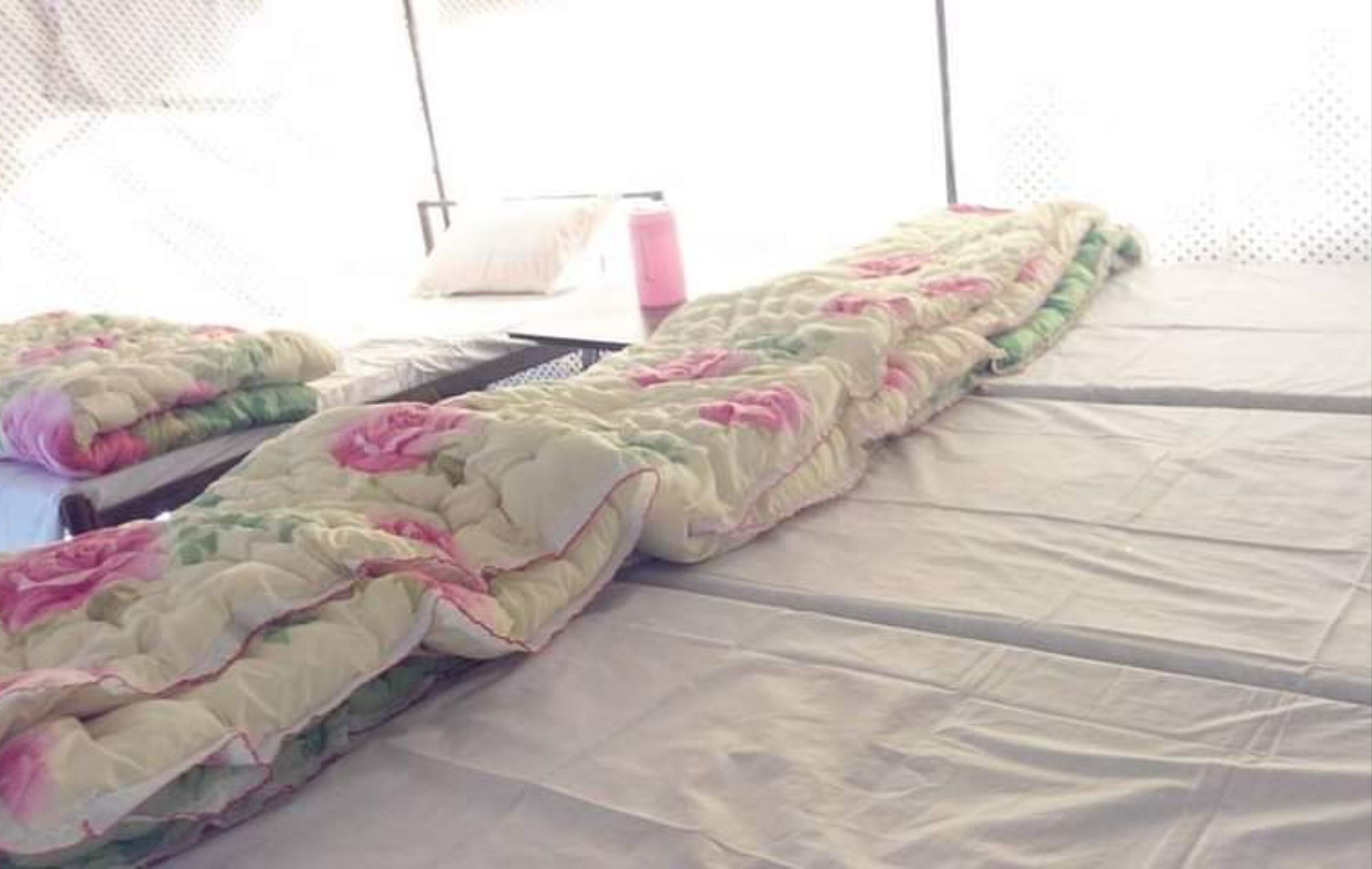 A bed with a floral-patterned quilt and a white sheet.