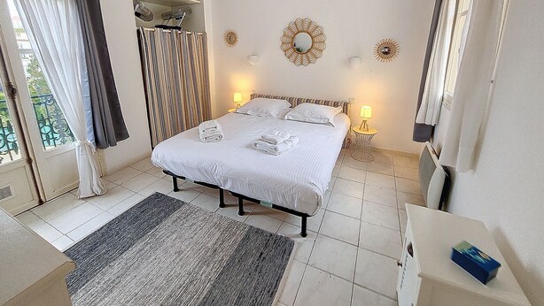 A bedroom with a bed, bedside lamps, a rug, and curtains. - HENRI CAMILLE REAL ESTATE - Florida 2 - 2 bedrooms close center (Cannes)