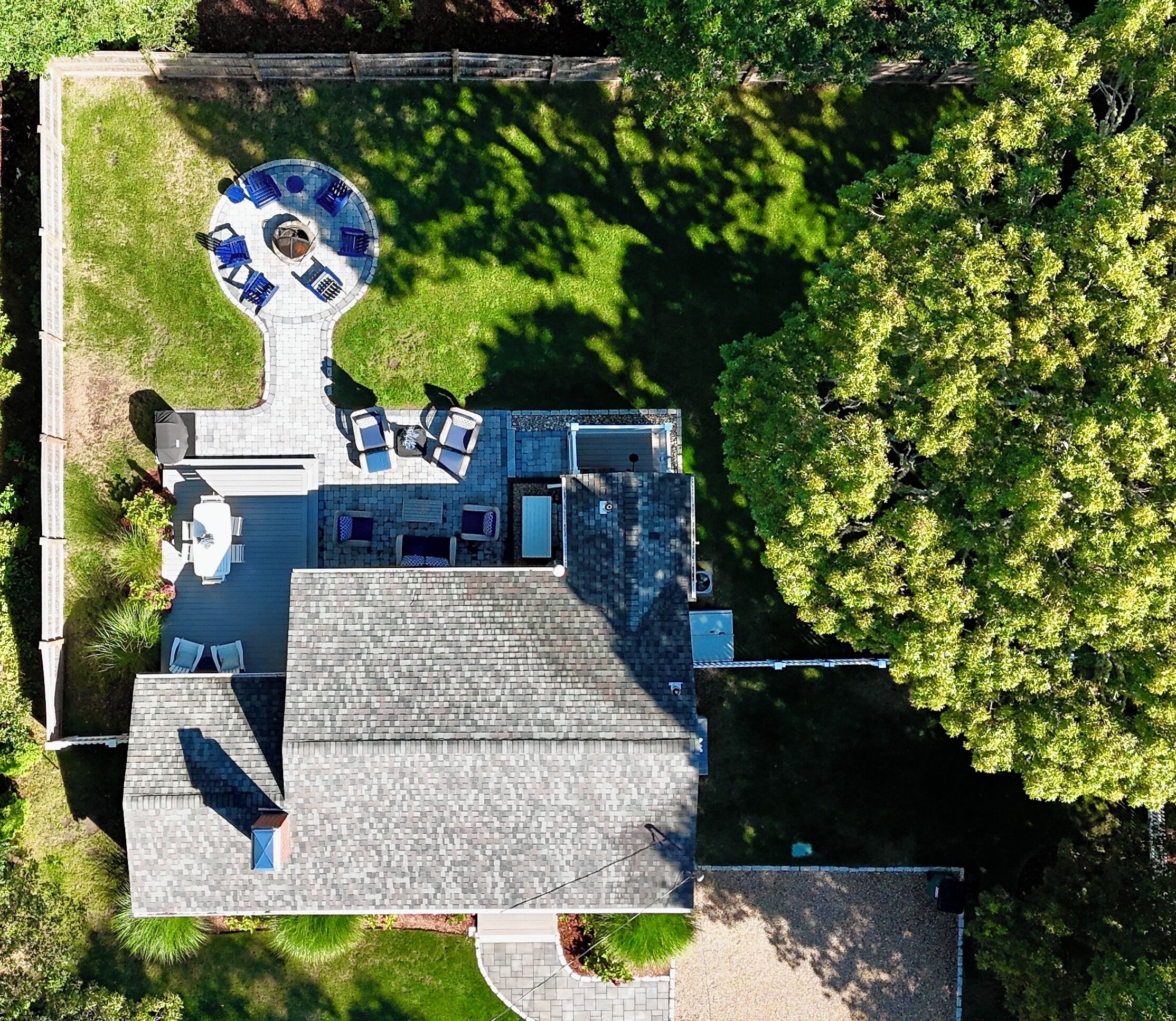 Luchtbeeld van een woonhuis met een rond terras, buitenmeubilair en een overdekt gedeelte.