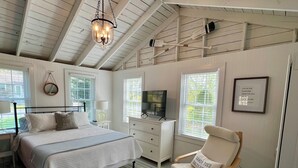 Ein Schlafzimmer mit einem Bett, einem Sessel, einem Fernseher und einem Deckenventilator.