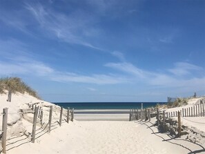 A sandy beach path leading to the ocean, flanked by wooden fences and sparse vegetation. - Dennis: 16 beaches, tennis, golf, bike trail, Fire-pit, 5-Start restaurants (Dennis)