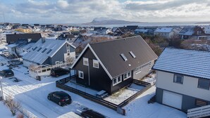 A residential area with houses featuring sloped roofs and a prominent mountain in the background. - 3BR - Townhouse - Free Parking -Tórshavn (Hoyvík)