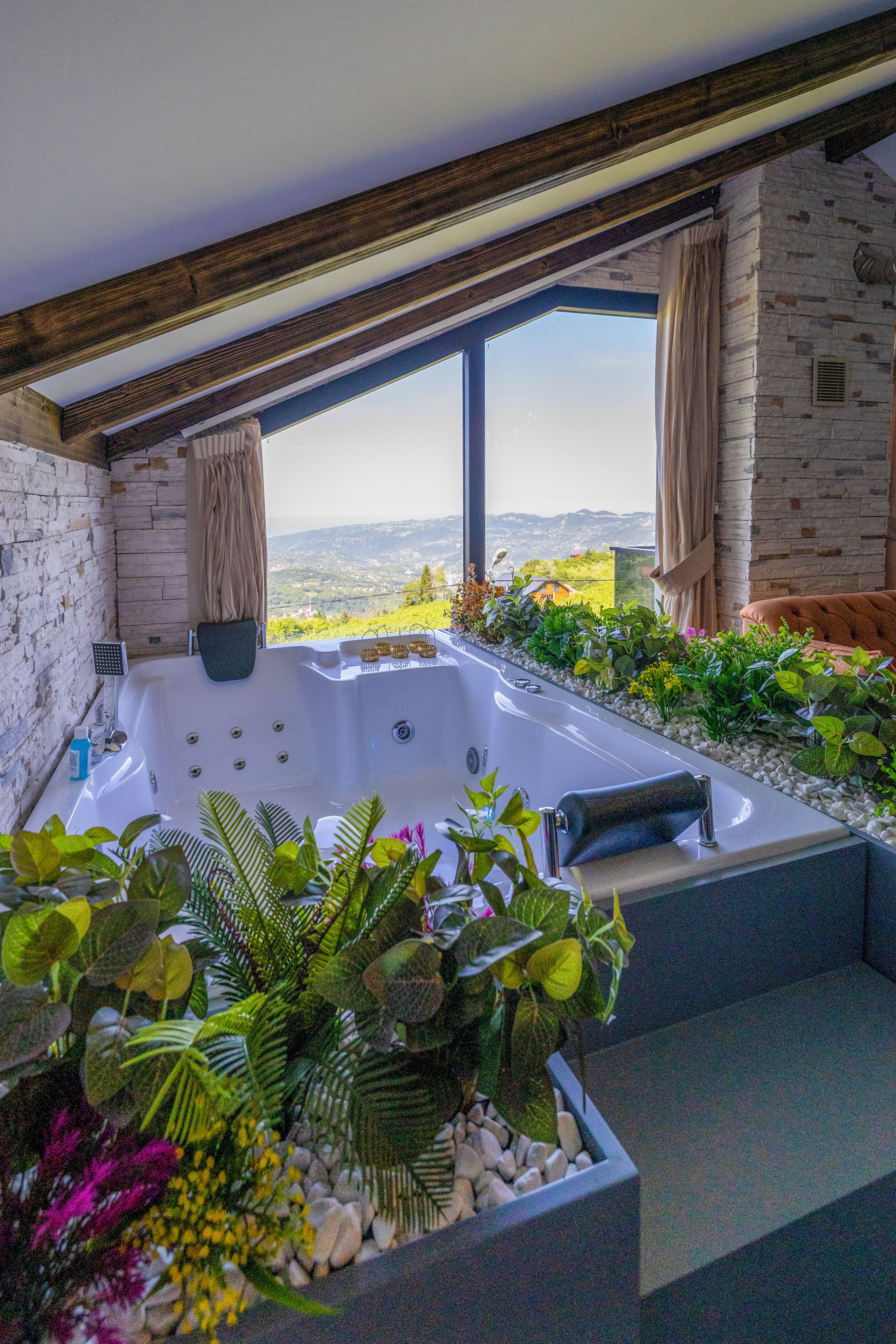 A spa area with a hot tub, surrounded by plants and a view of the countryside.