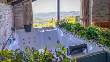 A spa area with a hot tub, surrounded by plants and a view of the countryside.