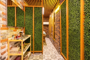 A narrow hallway with a brick wall on one side and a wooden wall with green foliage on the other. There is a wooden shelf with various items on it. - Poison Garden Suite & SPA (Trabzon)