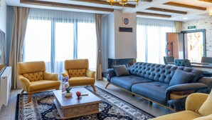 Een woonkamer met een bank, fauteuils, een salontafel en een kroonluchter.