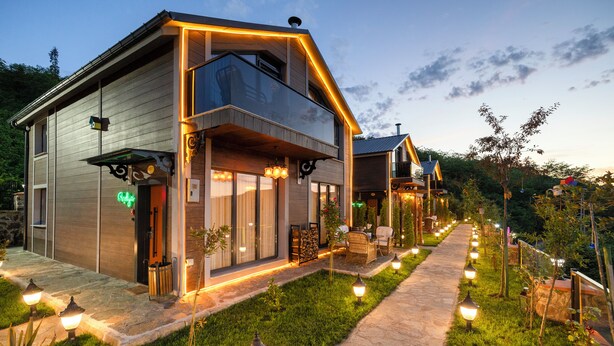 Een modern herenhuis met een stenen pad, buitenmeubilair en decoratieve verlichting.