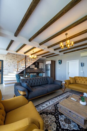 A modern living room with a staircase, wooden beams, and a kitchen in the background. - Poison Garden Suite & SPA (Trabzon)