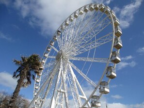 Une grande roue, avec ses cabines, se dressant sur un ciel bleu et dégagé.