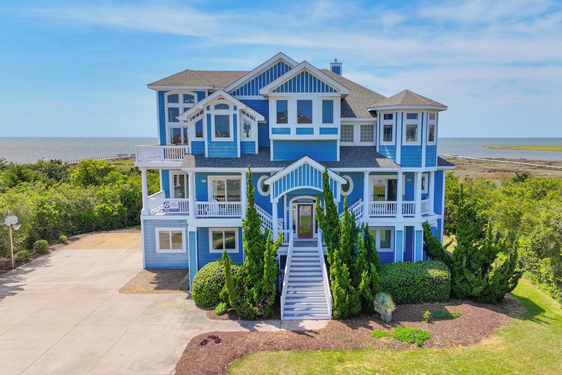 A two-story house with a front porch, a staircase, and a view of the ocean.