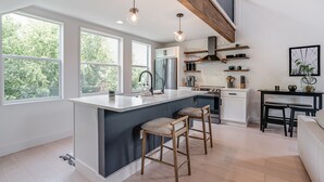 A modern kitchen with a central island, bar stools, and a dining area with a bench.