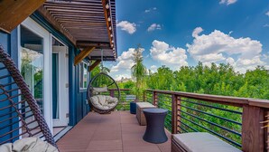 A balcony with a hanging chair, a small table, and a cushioned bench.