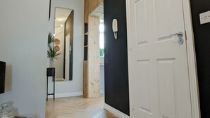 A hallway with a wooden floor, a white door, and a black wall.