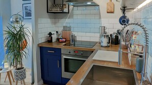 A modern kitchen with blue cabinets, a stainless steel sink, and a built-in oven.