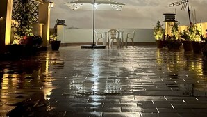 Spazio esterno con pavimento lastricato, tavolo e sedie, e un ombrellone grande.