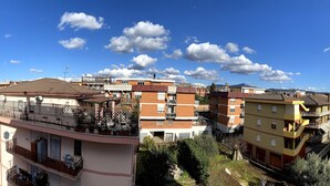 Un edificio residenziale a più piani con balconi, cielo sereno e vista sulla strada.