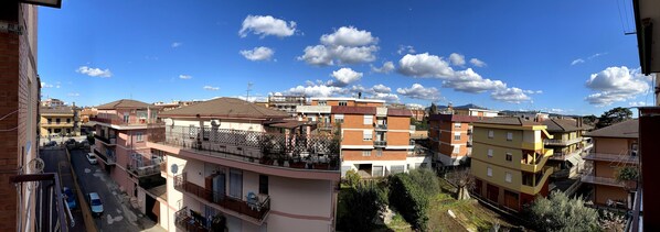 A multi-story residential building with balconies, a clear sky, and a street view. - Charming stay in Marino. (Marino)