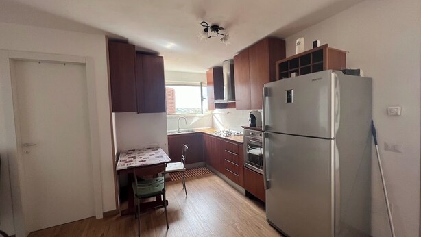 Una cucina compatta con frigorifero, forno e pensili in legno.