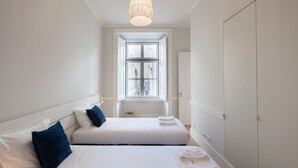 A hotel room with two beds, a large window, and a wardrobe. - FLH Praça Rossio Elegant Flat (Lisbon)