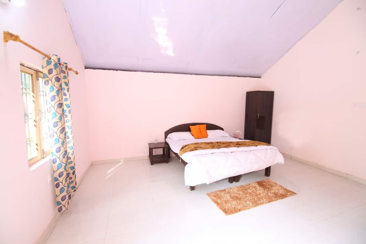 A bedroom with a bed, a nightstand, a wardrobe, a window with curtains, and a rug.