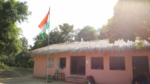 Um pequeno edifício com telhado de palha, um mastro com a bandeira indiana e algumas janelas.