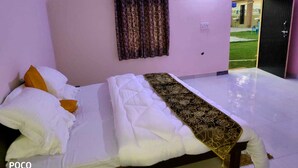 Quarto com cama, almofadas, cobertor e cortina.