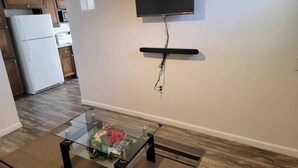 Ett modernt kök med träskåp, ett vitt kylskåp och en platt-TV som är monterad på väggen.