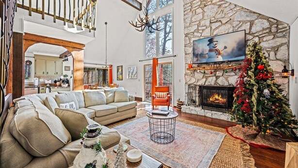A spacious living room with a large sectional sofa, a fireplace, a Christmas tree, and a stone accent wall. - Hillside Hideaway/Views/Hot Tub/Fireplace & Pit (Maggie Valley)