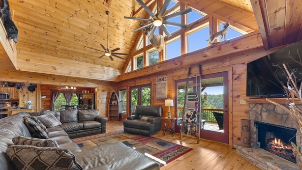 A spacious living room with a fireplace, leather sofas, and a large window overlooking a scenic view. - 🌄Sleeps up to 16 🌄 Pristine Mountain Views from Downtown Helen ⛰️ (Helen)