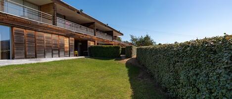 A modern two-story house with a well-maintained lawn and a tall hedge.